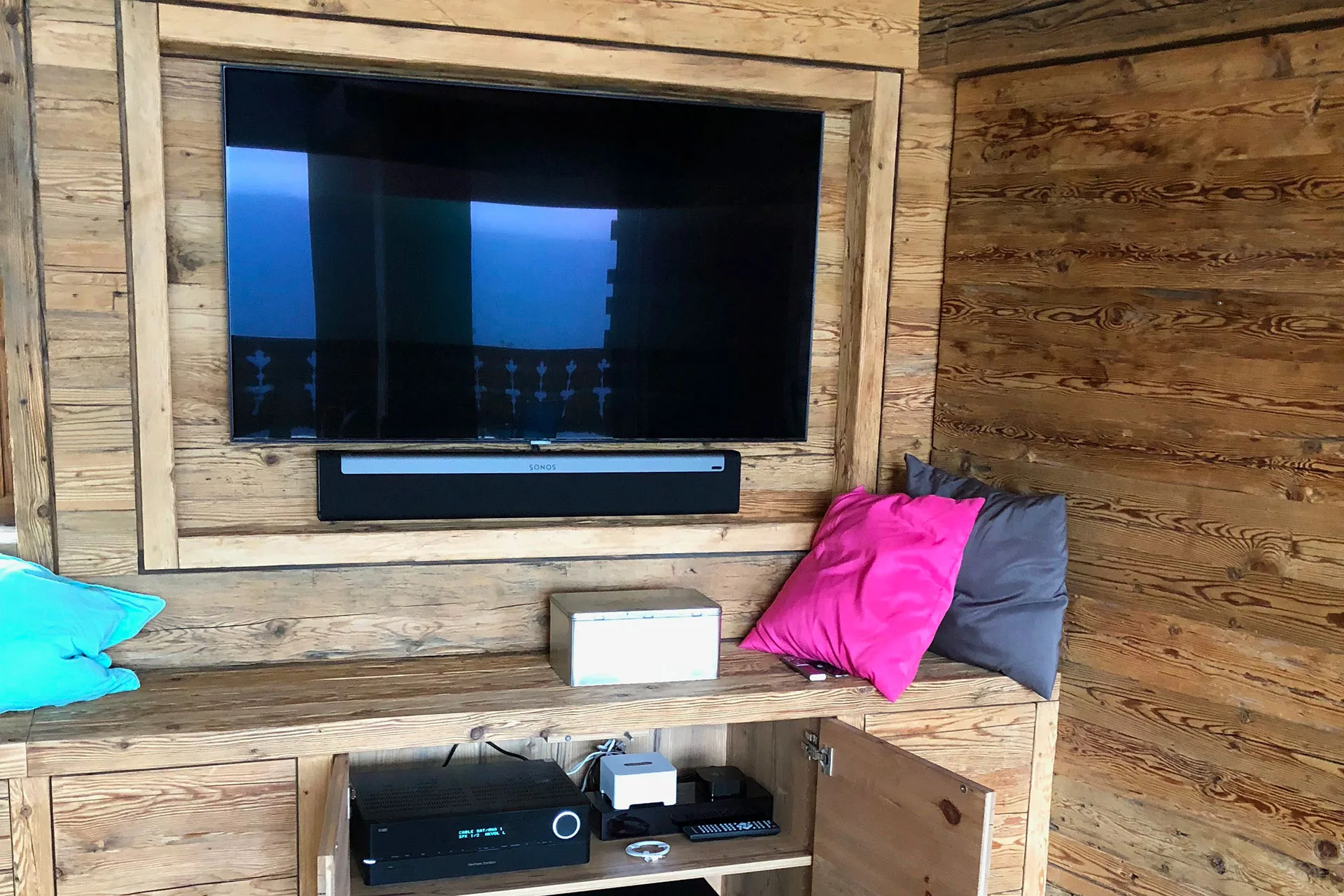 Téléviseur et barre de son encastrés dans un meuble en vieux bois de chalet
